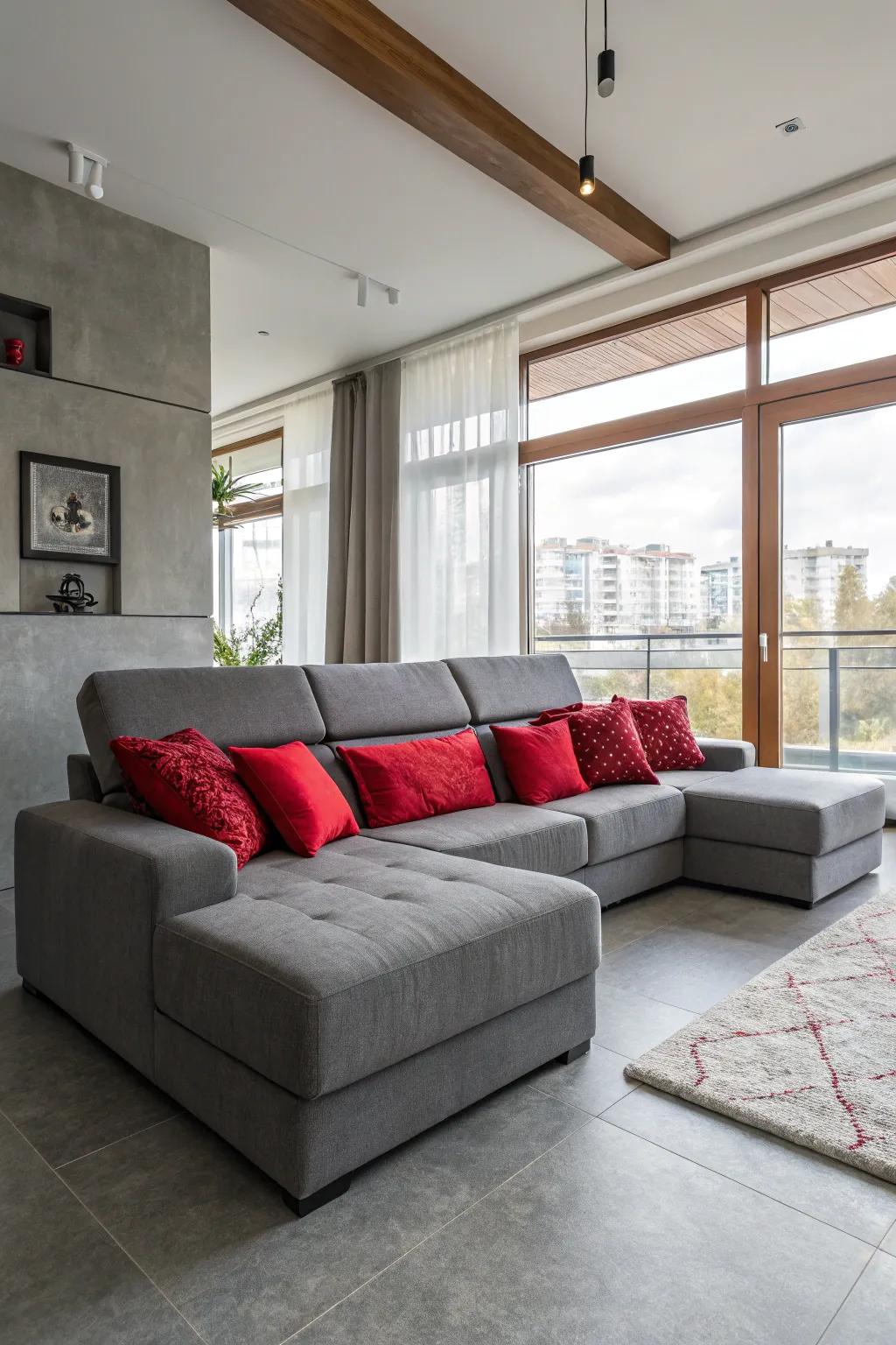 A cozy living room featuring a grey sectional and red cushions.