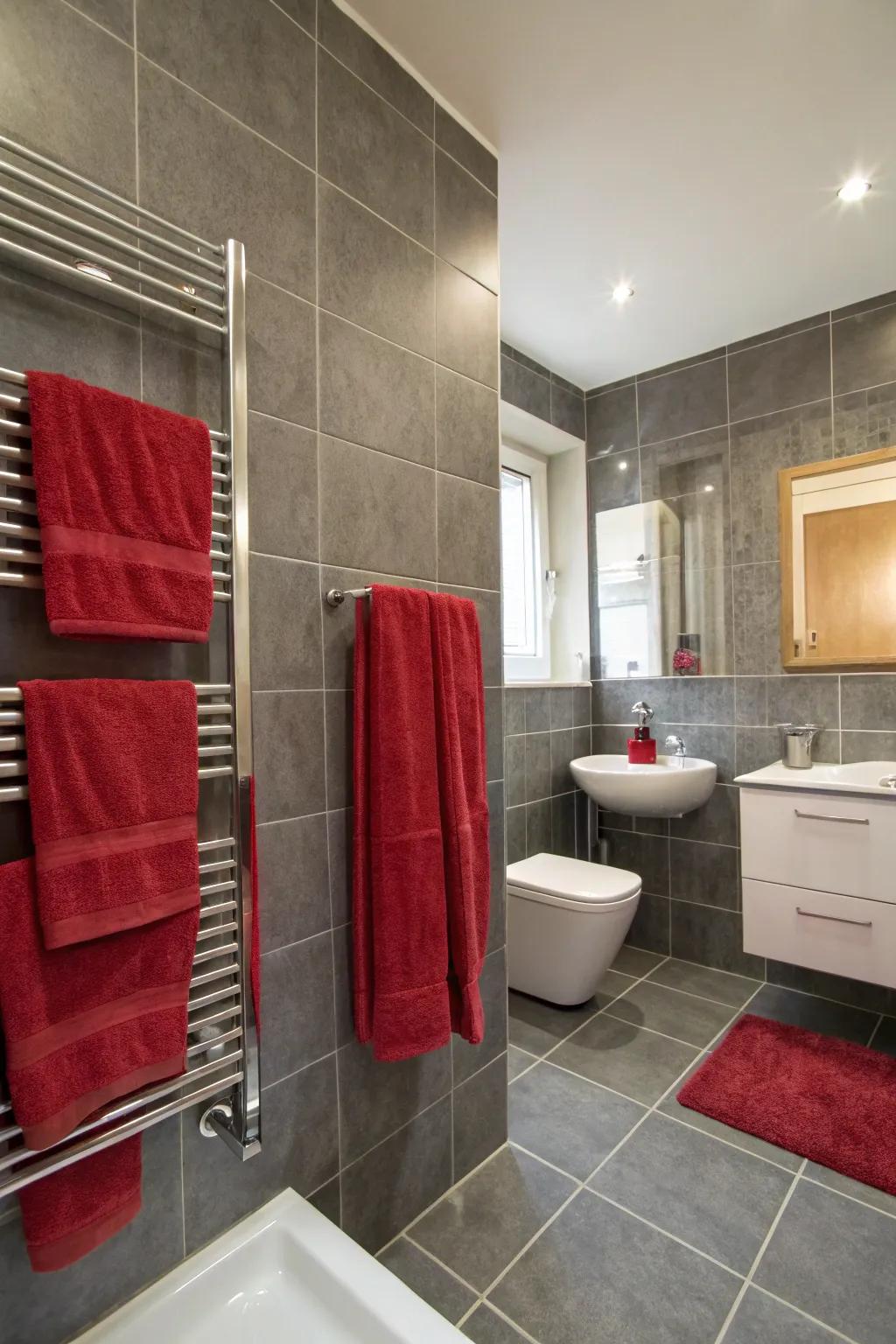 A bathroom featuring grey tiles and a splash of red.